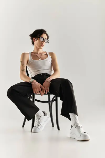 Um jovem magro mostra sua roupa na moda em um cenário de estúdio limpo, posando com confiança. — Fotografia de Stock