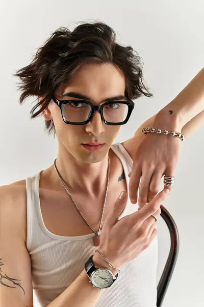 A slim young man in a white tank top poses stylishly, exuding confidence and trendiness. — Stock Photo