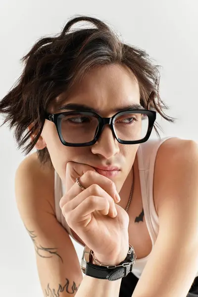 Slim young man in a white tank top looks contemplative in a bright studio, showcasing style. — Stock Photo