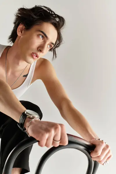 A fashionable young man poses in a sleek studio wearing a white tank top, exuding confidence. — Stock Photo
