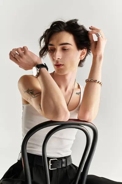 A slim young man dressed in a white tank top poses thoughtfully in a minimalist studio. — Stock Photo