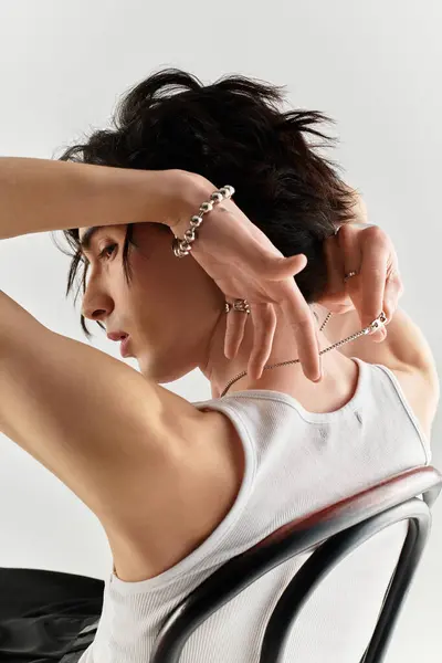 A slim young man in a white tank top poses confidently in a stylish studio, highlighting fashion. — Stock Photo
