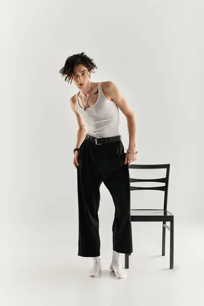 A slim young man poses confidently in a white tank top against a neutral backdrop. — Stock Photo