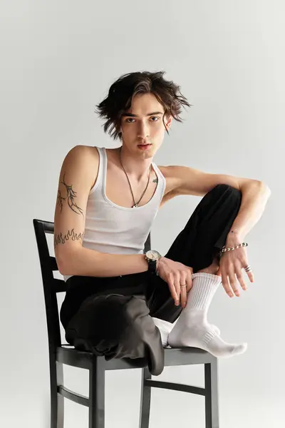 Um jovem magro em um top tanque branco exibe moda moderna com uma pose relaxada. — Fotografia de Stock