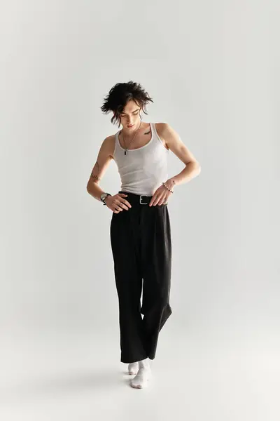 A young man in a white tank top presents a stylish look in a contemporary studio setting. — Stock Photo