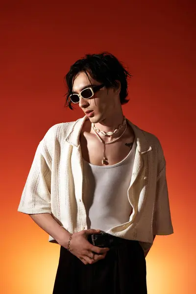A stylish young man poses confidently in a trendy summer outfit against a warm backdrop. — Stock Photo