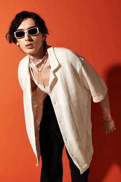 A slim young man showcases a trendy summer outfit in a vibrant studio setting. — Stock Photo
