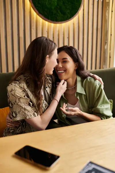 Two women embracing in a vibrant cafe, sharing laughter and deep connection over drinks. — Stock Photo
