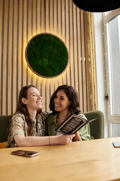 A lesbian couple enjoys each others company while looking over the menu at a quaint cafe. — Stock Photo