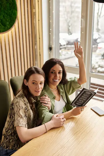 Zwei Frauen interagieren herzlich, während sie an einem verschneiten Tag in einem schönen Café in der Speisekarte blättern. — Stockfoto