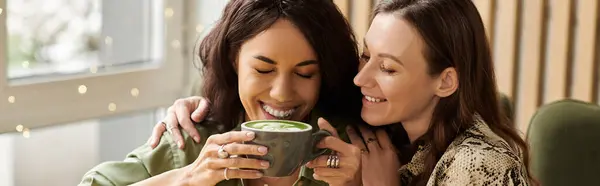Two women embrace warmly while enjoying a delicious drink at a delightful cafe filled with laughter. — Stock Photo