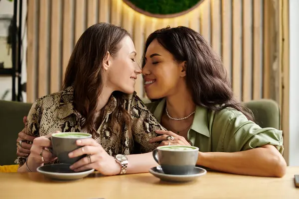 Zwei Frauen umarmen sich herzlich an einem Cafétisch, genießen Gesellschaft und Getränke. — Stockfoto