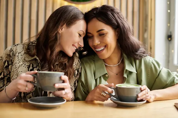 Two women enjoy each others company at a cafe, sharing smiles and warm beverages. — Stock Photo
