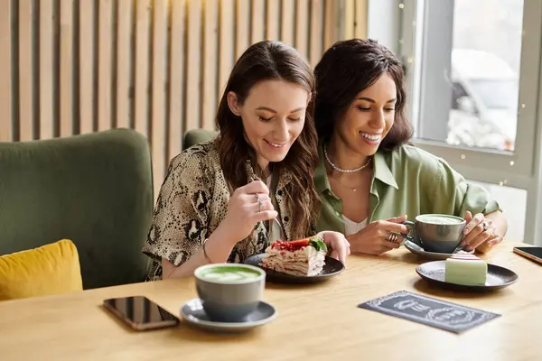 In un incantevole caffè, due donne godono di deliziosi dessert e bevande calde mentre condividono sorrisi.. — Foto stock
