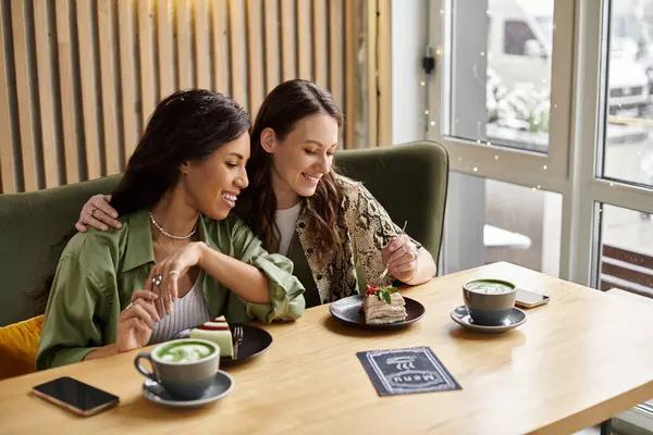 Two women share laughter and dessert, savoring each others company at a warm cafe setting. — Stock Photo