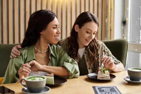 Two women share laughter and dessert at a charming cafe, celebrating love and connection. — Stock Photo