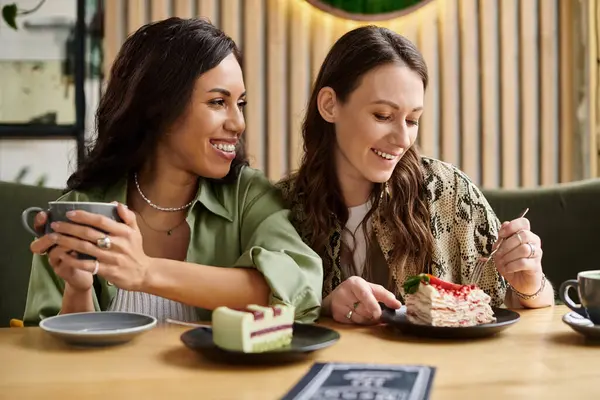 Two women enjoy sweet treats and coffee at a charming cafe, sharing smiles and laughter together. — Stock Photo