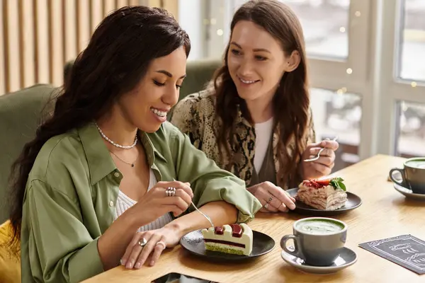 Two women are enjoying each others company while tasting delightful cakes at a charming cafe. — Stock Photo