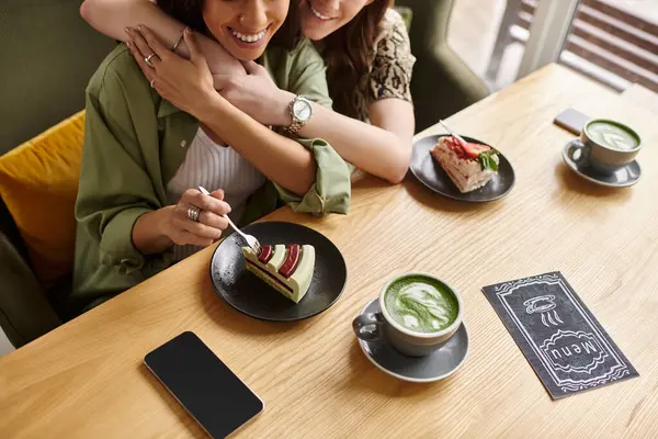 Two women share a moment of bliss over delicious cakes and drinks at an inviting cafe. — Stock Photo