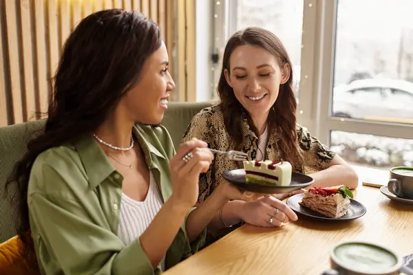 Two women smile as they share delicious desserts and laughter inside a charming cafe. — Stock Photo