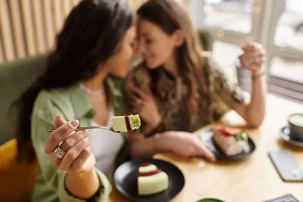 Two women savor delicious desserts while enjoying each others company in a warm cafe. — Stock Photo