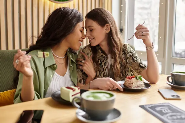 Two women share a tender moment while enjoying dessert and coffee together at a charming cafe. — Stock Photo