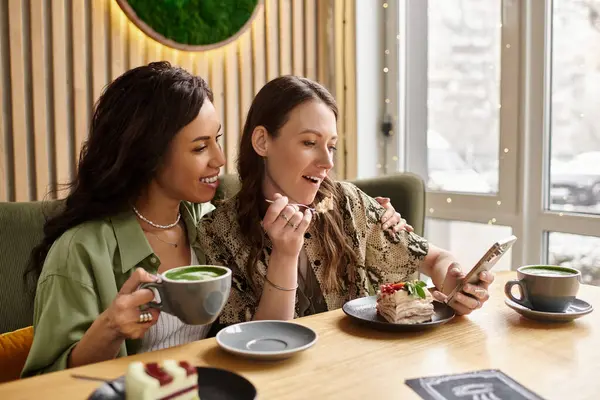 A joyful lesbian couple enjoys each others company while sipping drinks and sharing dessert. — Stock Photo