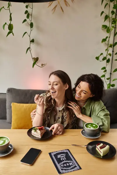 Two women share laughter and delicious desserts in a charming cafe, creating happy memories. — Stock Photo