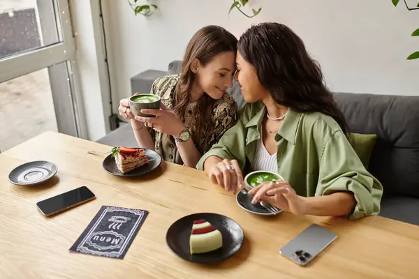 At a charming cafe, a couple enjoys intimate moments while savoring drinks and desserts together. — Stock Photo