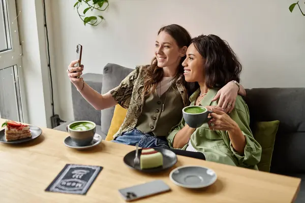 Two women share a warm moment in a cozy cafe over green tea. — Stock Photo