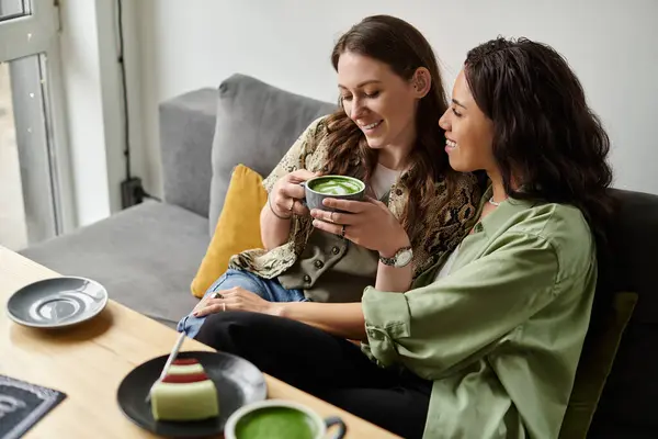 Two women enjoy each others company while sipping tea and sharing delightful treats in a warm cafe. — Stock Photo