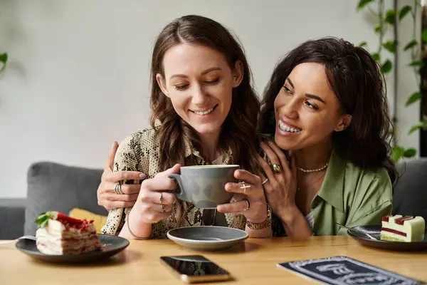 Two women share a joyful moment at a cafe while enjoying coffee and dessert together. — Stock Photo