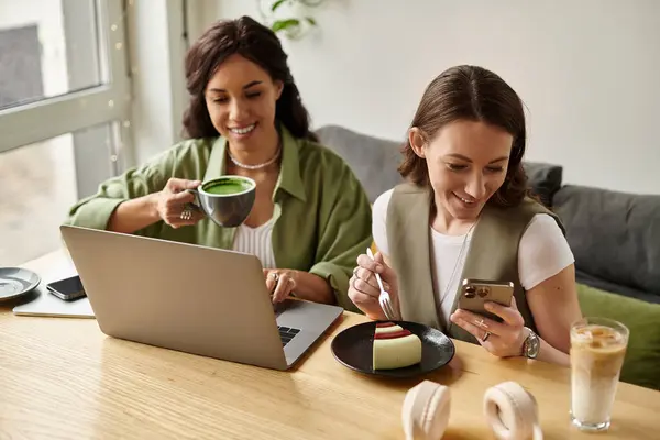 A cheerful lesbian couple enjoys time together, sipping drinks and sharing treats at a cafe. — Stock Photo