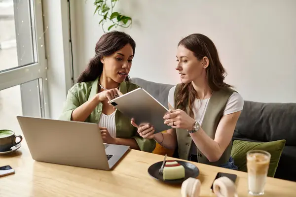 Two women collaborate at a stylish cafe, discussing creative projects while enjoying drinks. — Stock Photo
