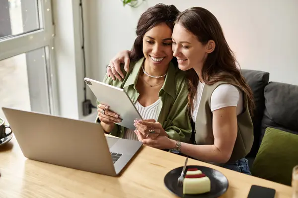 Two women enjoy each others company at a cafe while looking at a tablet. — Stock Photo