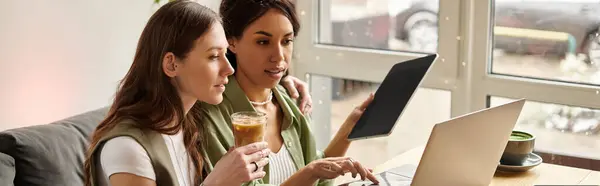Couple sits closely at a cafe, focused on their laptop and tablet, sharing ideas and drinks. — Stock Photo