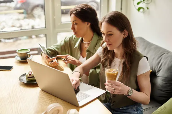 Two women share a delightful moment in a cafe, engaging with their work and each other. — Stock Photo