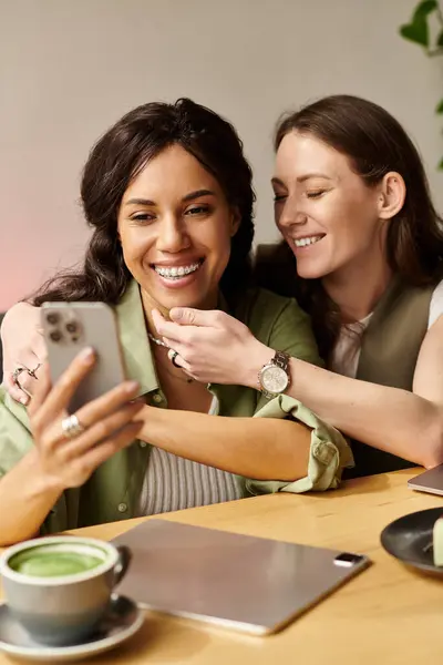 Zwei Frauen lächeln und lachen zusammen, während sie ihren Kaffee an einem urigen Café-Tisch genießen. — Stockfoto