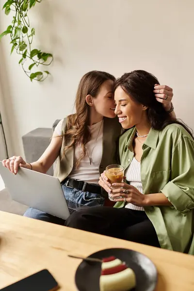 Dos mujeres disfrutan de la compañía, sonriendo y abrazándose mientras beben en un café. - foto de stock