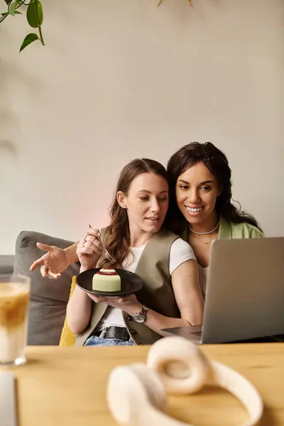 Two women share smiles and a slice of cake while engaged in conversation at a cafe. — Stock Photo