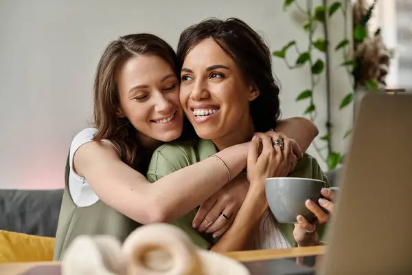Zwei Frauen umarmen sich in einem Café herzlich, teilen Lächeln und Lachen beim gemeinsamen Kaffee. — Stockfoto