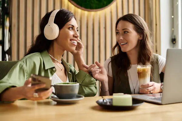 Two women enjoy each others company over drinks in a warm, inviting cafe atmosphere. — Stock Photo