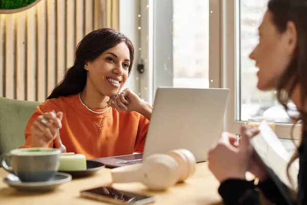 Two women share joyful moments over coffee in a vibrant cafe, connecting and enjoying life. — Stock Photo