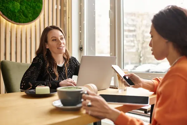 Two women enjoy each others company in a welcoming cafe, exchanging smiles and warmth. — Stock Photo
