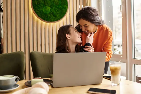 Two women embrace affectionately in a welcoming cafe, lost in blissful conversation and connection. — Stock Photo