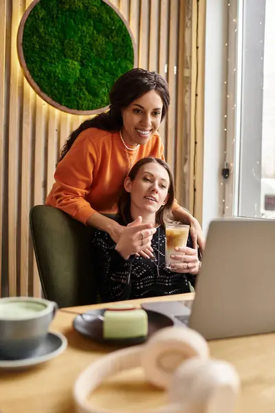 Two women share laughter and tenderness over drinks while enjoying a lovely cafe atmosphere. — Stock Photo
