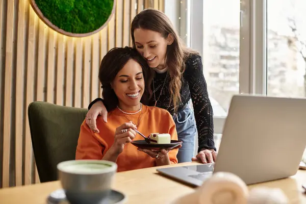 Two women enjoy dessert together while sharing smiles and laughter in a warm cafe setting — Stock Photo