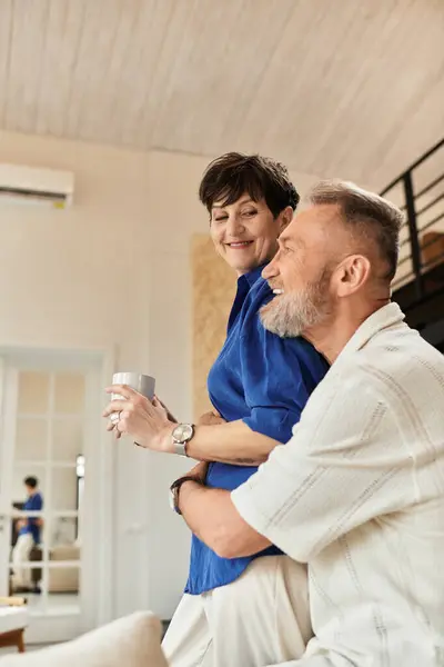 A cheerful husband embraces his wife as they enjoy their time together at home. — Stock Photo