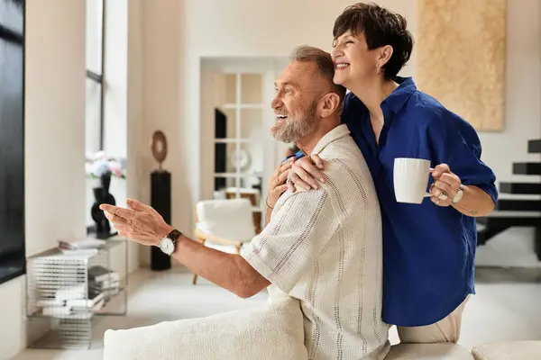 A joyful husband and wife share laughter while relaxing at home in their cozy living space. — Stock Photo