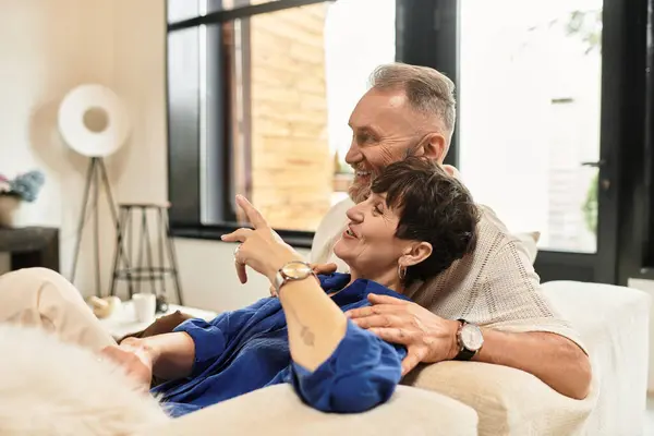 Couple relaxes on a comfortable couch, sharing smiles and playful conversation in their home. — Stock Photo